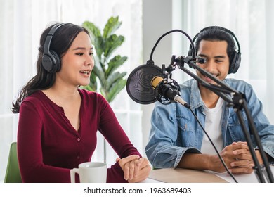 Smile Two Asian Young Woman, Man Radio Hosts In Headphones, Microphone While Talk, Conversation, Recording Podcast In Broadcasting At Studio Together. Technology Of Making Record Audio Concept.