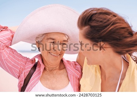 Smile, wind and senior mother on beach with daughter in summer for travel, holiday or vacation. Face, love or bonding with woman and happy elderly parent outdoor together for weekend getaway