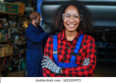 Smiled Mechanic Woman With Background Of Male Mechinic Working In Auto Shop.