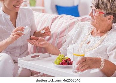 Smiled nurse preparing the dose of daily pills to senior patient - Shutterstock ID 462553546