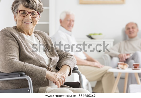 Smiled woman on a\
wheelchair at nursing\
home