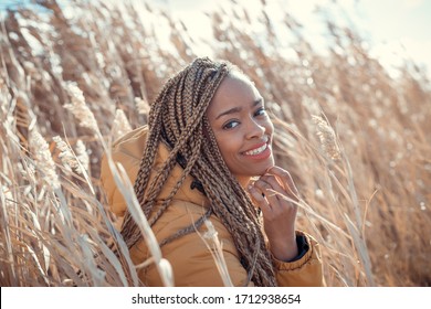 smiley African American girl in wheat field. blonde african braids. yellow coat . sunny day