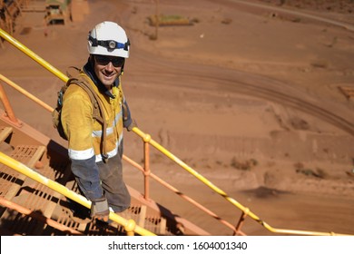 Smiley construction miner wearing safety helmet glove dressing work uniform having a break walking down stairs maintenance safety fall prevention using holding handrails three points of contact     