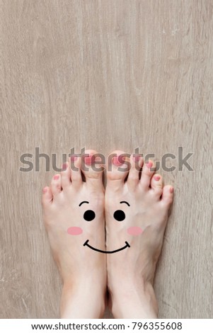 Smiley Face Drawn on Toes. Close Up Female Barefoot On Wooden Floor Background Great for Any Use.