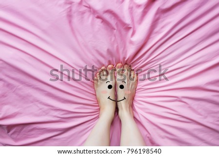 Smiley Face Emotion Barefoot. Beautiful Female Feet on Pink Fabric Bedroom Background Great for Any Use.