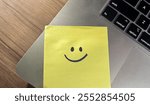 Smiley Face on yellow sticky note on a laptop. Sticky note on laptop with smiley on it. Gesture of appreciation or saying sorry.