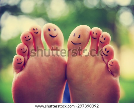 smiley faces on a pair of feet on all ten toes (VERY SHALLOW DOF - big toe on the right) in a park setting toned with a retro vintage instagram filter app or action effect