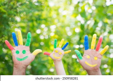 Smiley On Hands Against Green Spring Background. Family Having Fun Outdoors