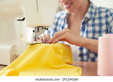 smiley woman sewing on sewing-machine. focus on sewing-machine