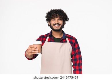 Smiley young Indian bar tender barista holding coffee cup isolated over white background. Hindi man selling serving hot beverages wearing apron - Powered by Shutterstock