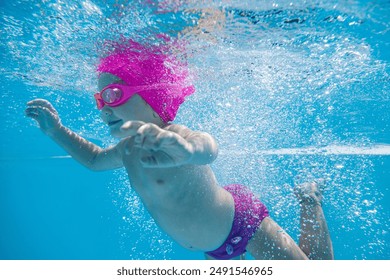 smiling 2 year old girl diving underwater in a pool of clear water among bubbles for swimming lesson - Powered by Shutterstock