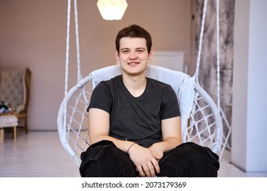 Smiling 23 Years Old Man In Hanging Chair Indoors.