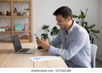 Smiling 35s Hispanic businessman, office employee hold cellphone sit at workplace, check e-mail app, usage of mobile business application, comfort easy life use modern wireless tech at work concept - Powered by Shutterstock