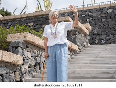 Smiling 70 year old elderly woman with walking disability holding stick knob while walking down stairs outdoors, leaning on stick, suffering from muscle problems, bone disease, recovering from trauma - Powered by Shutterstock