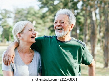 Smiling Active Senior Couple Jogging Exercising And Having Fun And Laughing Together Taking A Break In The Park