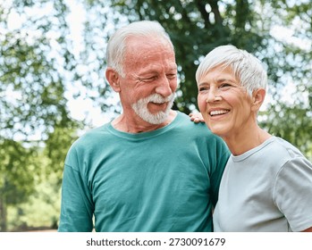 Smiling active senior couple jogging exercising and having fun and laughing together taking a break in the park