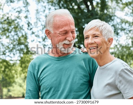 Smiling active senior couple jogging exercising and having fun and laughing together taking a break in the park