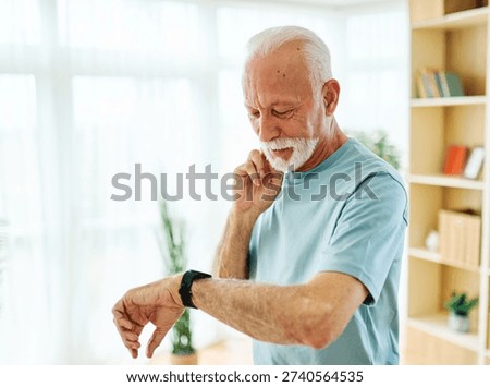 Smiling active senior man exercising taking a break on the mat at home or in the gym, senior athlete checking his heart rate and performance with smartwatch