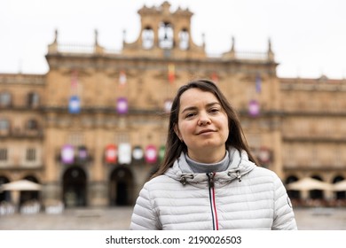 Smiling Adult Female Tourist Enjoying Walking In Ancient Spanish City Of Salamanca On Spring Day, Posing In Central Plaza Mayor..