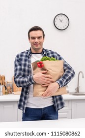 Smiling Adult Man Carrying Grocery Store Bag At Kitchen And Looking At Camera