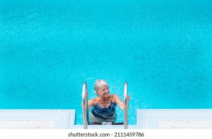 Smiling Adult Mature Woman In Outdoor Swimming Pool. Gray Haired Happy Elderly Grandmother Enjoying Swim Freedom And Retirement. Travel, Summer And Holiday Concept. Copy Space