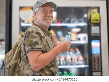 Smiling adult senior man with hat choosing snacks and drinks on 24h free automated distributor - people buying food on airport gate - travel lifestyle - Powered by Shutterstock