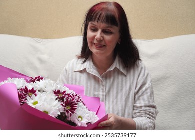 Smiling adult woman considering large bouquet of chrysanthemums given as a gift for Birthday, Mother's Day or Valentine's Day - Powered by Shutterstock