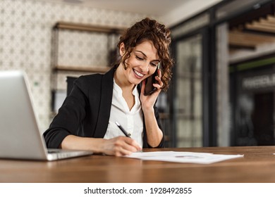 Smiling adult woman, making phone call at work.