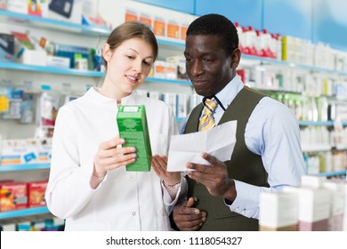 Smiling adult woman pharmacist discussing prescription medicines with man in pharmacy - Powered by Shutterstock