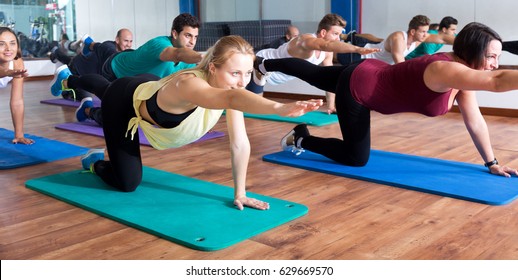Smiling adults having yoga class in sport club