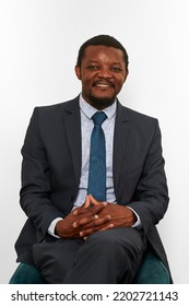 Smiling African American Black Man In Business Suit Sitting On Chair Isolated White Background. Happy Black Executive Businessman, Chief Executive Officer Satisfied Successful Interview With Applicant