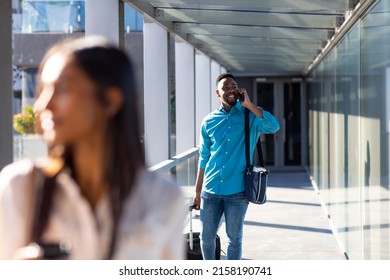 Smiling African American Businessman With Luggage Talking On Mobile Phone At Airport Corridor. Unaltered, Technology, Occupation, Business Travel And Transportation Concept.