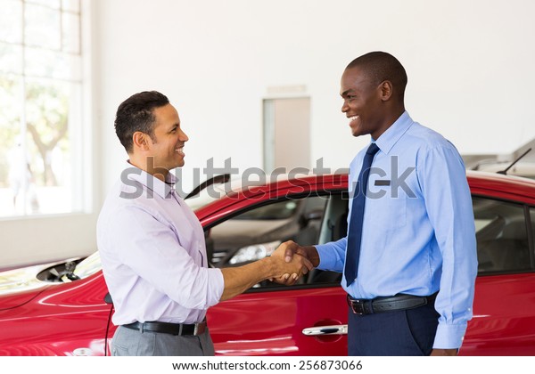 smiling african american car dealer handshake\
with customer