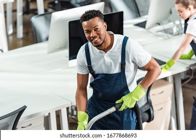 Smiling African American Cleaner Looking At Camera Near Young Colleague