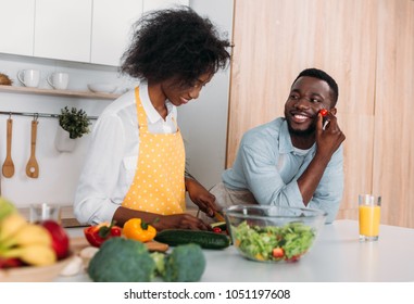 Smiling African American Couple In Aprons Cooking In Kitchen