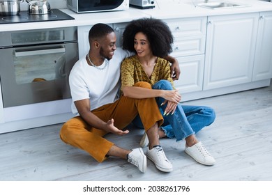 Smiling African American Couple Talking On Floor In Kitchen