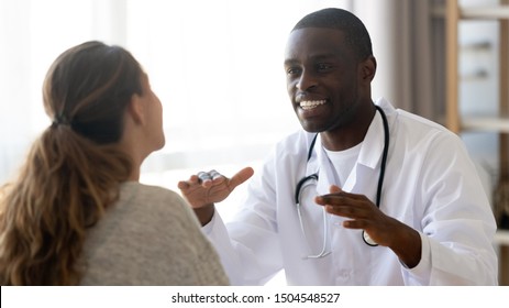 Smiling African American Doctor In White Uniform With Stethoscope Consulting Female Patient At Meeting, Discussing Medical Checkup Results Or Woman Complaint At Consultation, Offering Insurance