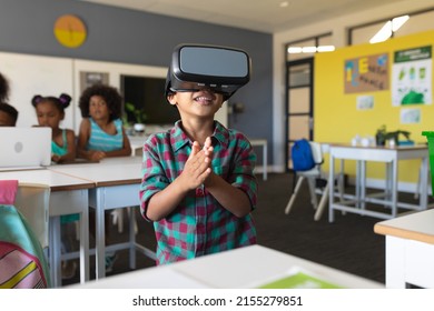 Smiling african american elementary schoolboy wearing vr glasses while standing in classroom. unaltered, education, virtual reality simulator, wireless technology and school concept. - Powered by Shutterstock