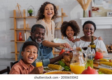 Smiling african american family looking at camera near thanksgiving dinner - Powered by Shutterstock