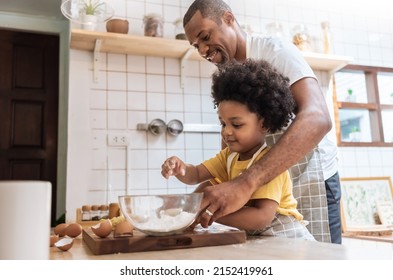 Smiling African American Father And Little Son While Cooking In Kitchen. Black Family Have Fun While Baking At Home