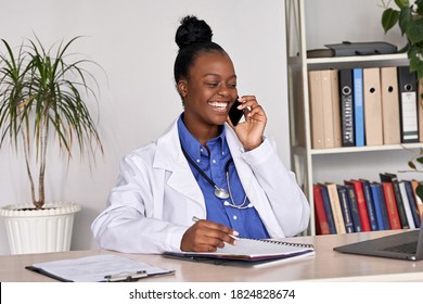 Smiling african american female doctor physician holding cell phone talking on mobile at work. Healthcare professional answering call giving remote consultation on smart phone making appointment notes