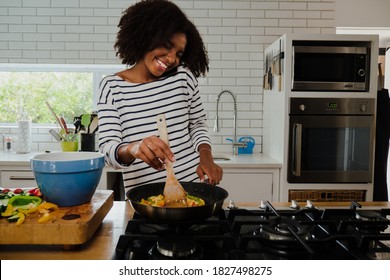 Smiling African American Female Making Delicious Dinner Chatting To Boyfriend On Smartphone Preparing For Date Night In Fancy Kitchen.