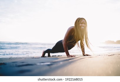 Smiling African American female trainer with casual figure feeling excited while doing push up plank during morning workout on beach, crossfit exercise and healthy lifestyle weight loss concept - Powered by Shutterstock