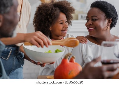 Smiling african american girl hugging grandmother during thanksgiving dinner