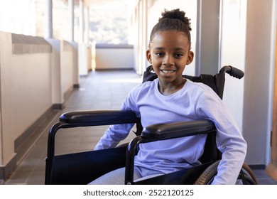 Smiling african american girl in wheelchair in school hallway, enjoying her day. education, inclusion, happiness, positivity - Powered by Shutterstock