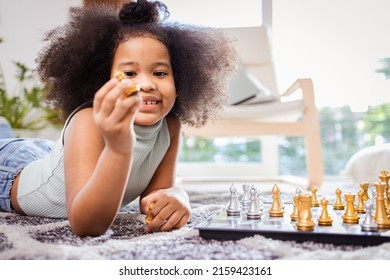 Smiling African American Girl While Playing Chess On The Floor In The Living Room At Home