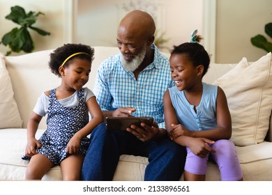 Smiling African American Girls With African American Grandfather Showing Digital Tablet. Unaltered, Wireless Technology, Family, Lifestyle, Childhood, Leisure Activity, And Domestic Life Concept.