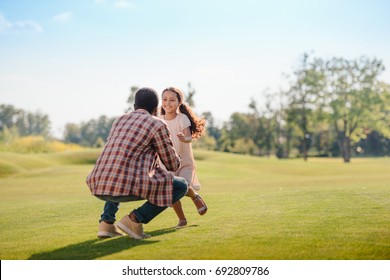 Smiling African American Granddaughter Running To Grandfather On Green Lawn In Park