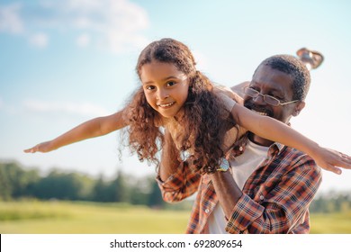 Smiling African American Grandfather Playing With Granddaughter At Sunny Day