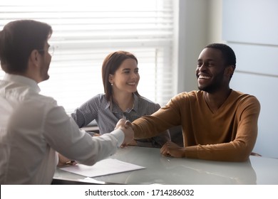 Smiling african american husband shaking hands with businessman in office. Happy successful business manager making deal with couple. Professional employee secured contract with gesture. - Shutterstock ID 1714286032